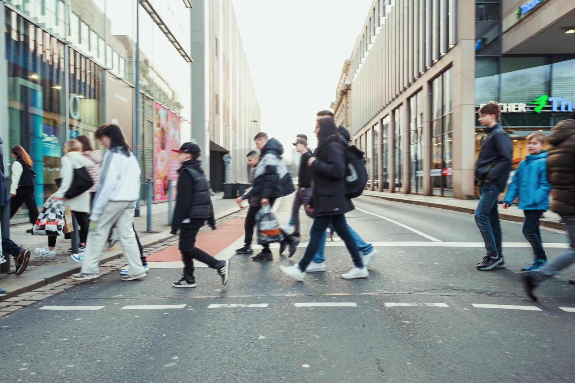 Menschen queren in einer Großstadt eine Hauptverkehrsstraße.