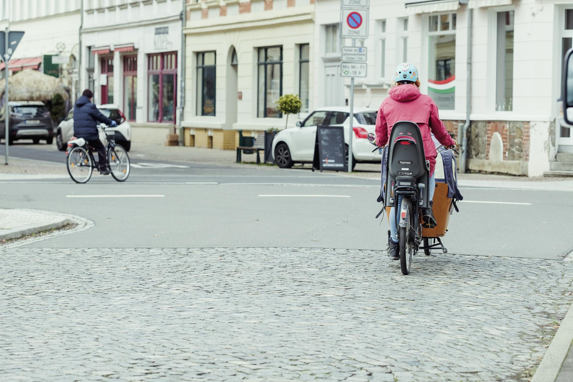 Eine Frau mit einem Lastenrad steht an einer Kreuzung.