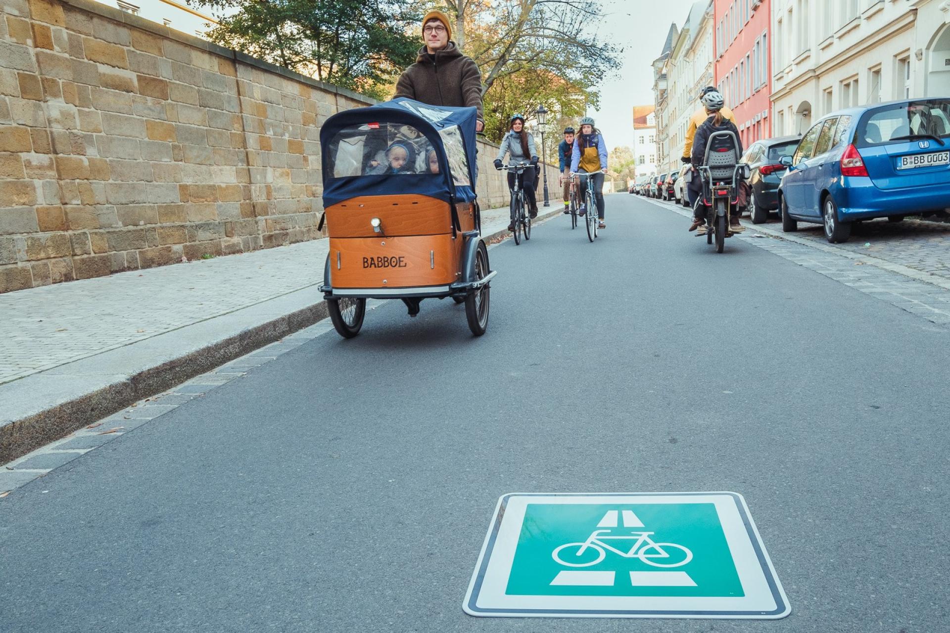 Mehrere Fahrräder fahren auf einer Straße. Einige davon sind Lastenräder.