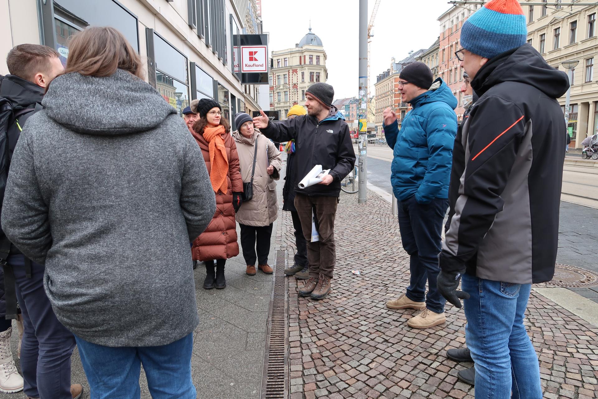 Menschen auf der Straße hören den Erklärungen einer Person zu.