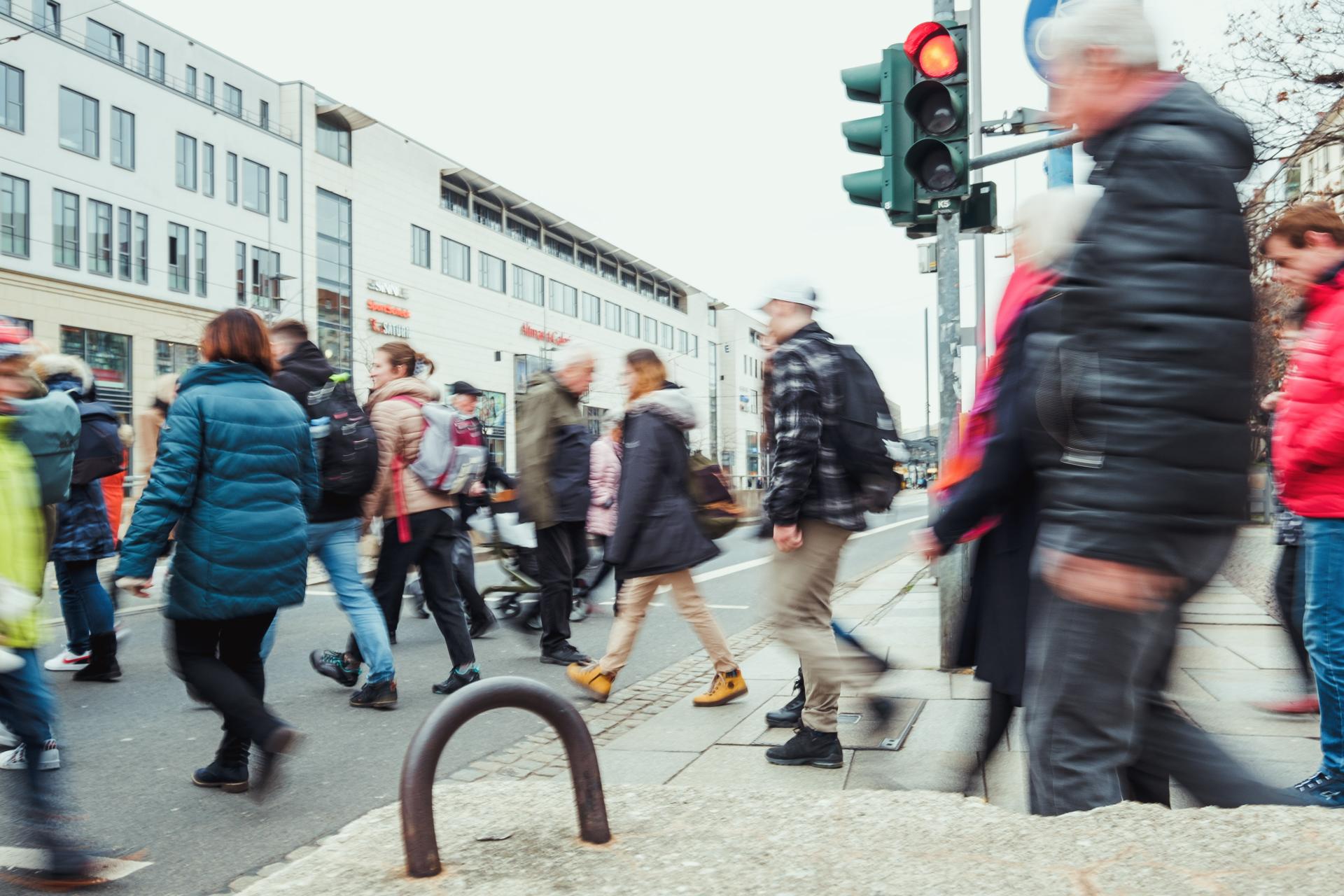 Viele Menschen überqueren an einer Ampel eine Straße zu Fuß.