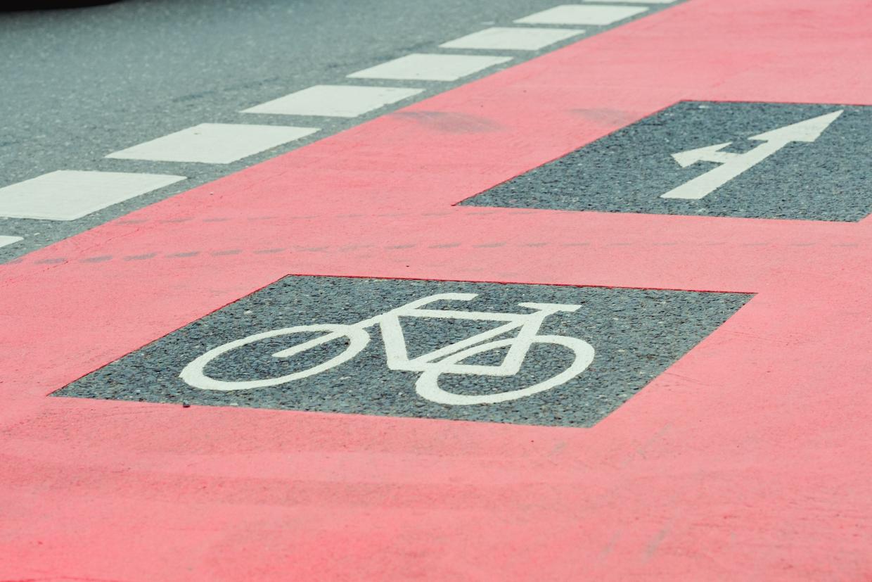 Rot markierter Radweg mit Fahrradsymbol und Richtungspfeil.