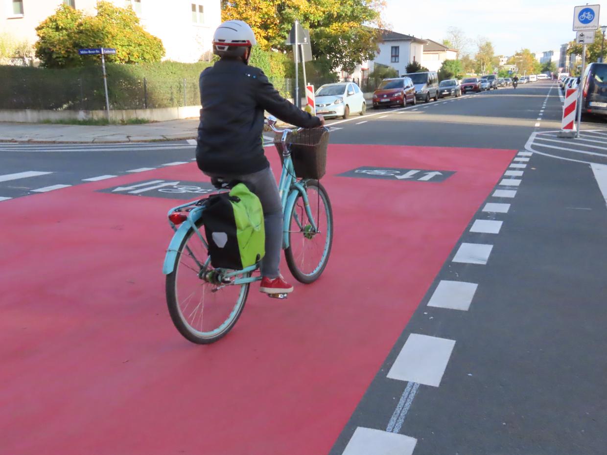 Eine Person fährt mit einem Fahrrad auf einem breiten, rot markierten Radweg.